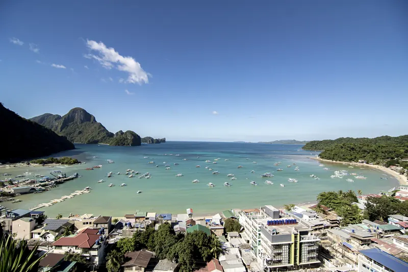 Vista desde lo alto del pueblo de El Nido y su bahía con decenas de bangkas, e islas de roca al fondo.