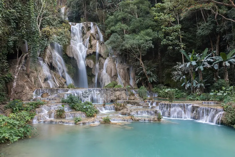 La cascada de Kuang Si cae entre la selva por escalones de roca hasta una poza de agua turquesa.